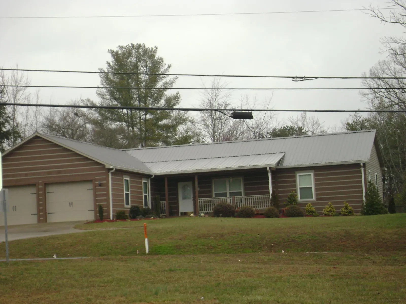 Gray metal roof on a log sided ranch home with a front porch in Groton